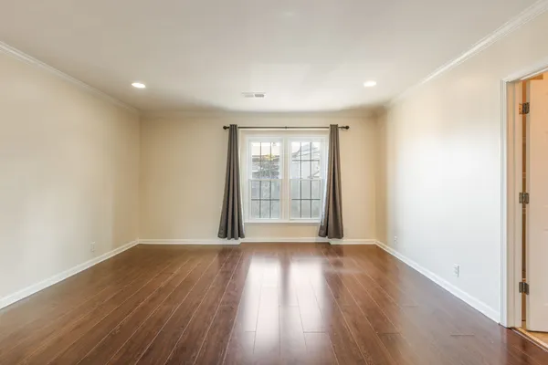 a view of an empty room with wooden floor and closet