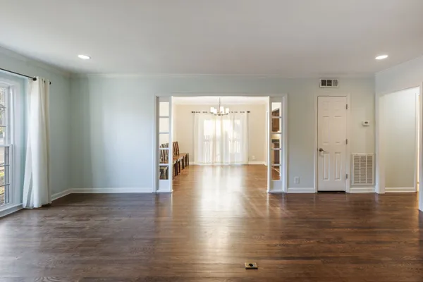 a view of an empty room with wooden floor and a fireplace