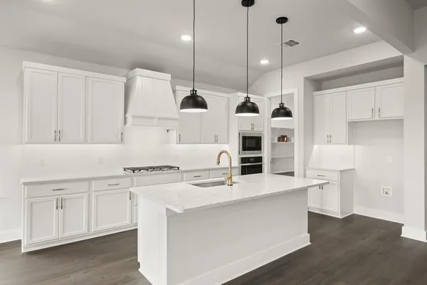 a large kitchen with stainless steel appliances a large counter top a stove a sink and a refrigerator