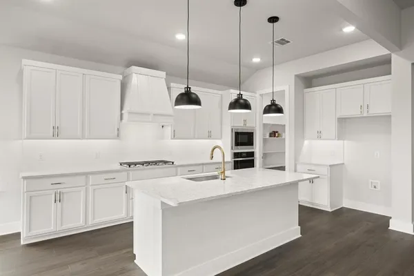 a large kitchen with stainless steel appliances a large counter top a stove a sink and a refrigerator