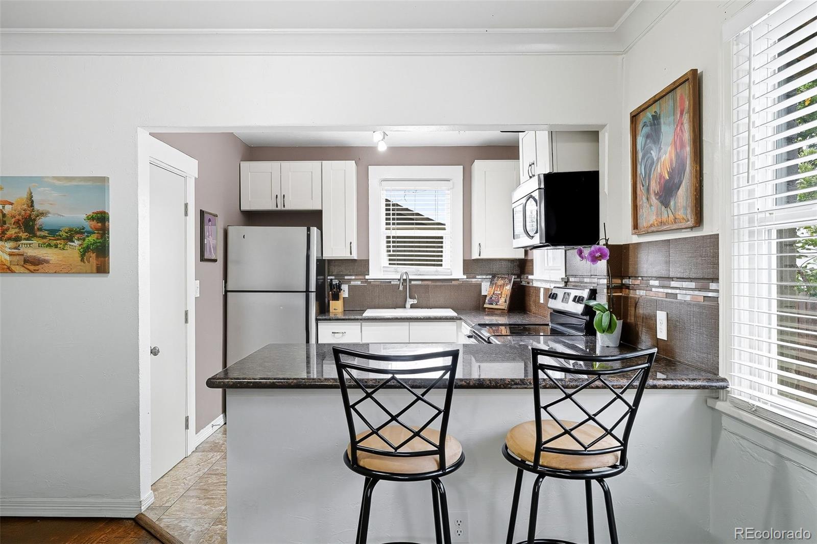 1280 Harrison Street Denver, CO 80206 - Photo 16 of 50 a kitchen with stainless steel appliances kitchen island a table chairs in it and a window