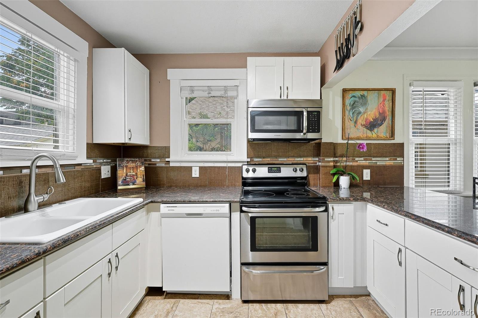 1280 Harrison Street Denver, CO 80206 - Photo 19 of 50 a kitchen with granite countertop a stove a sink and a microwave