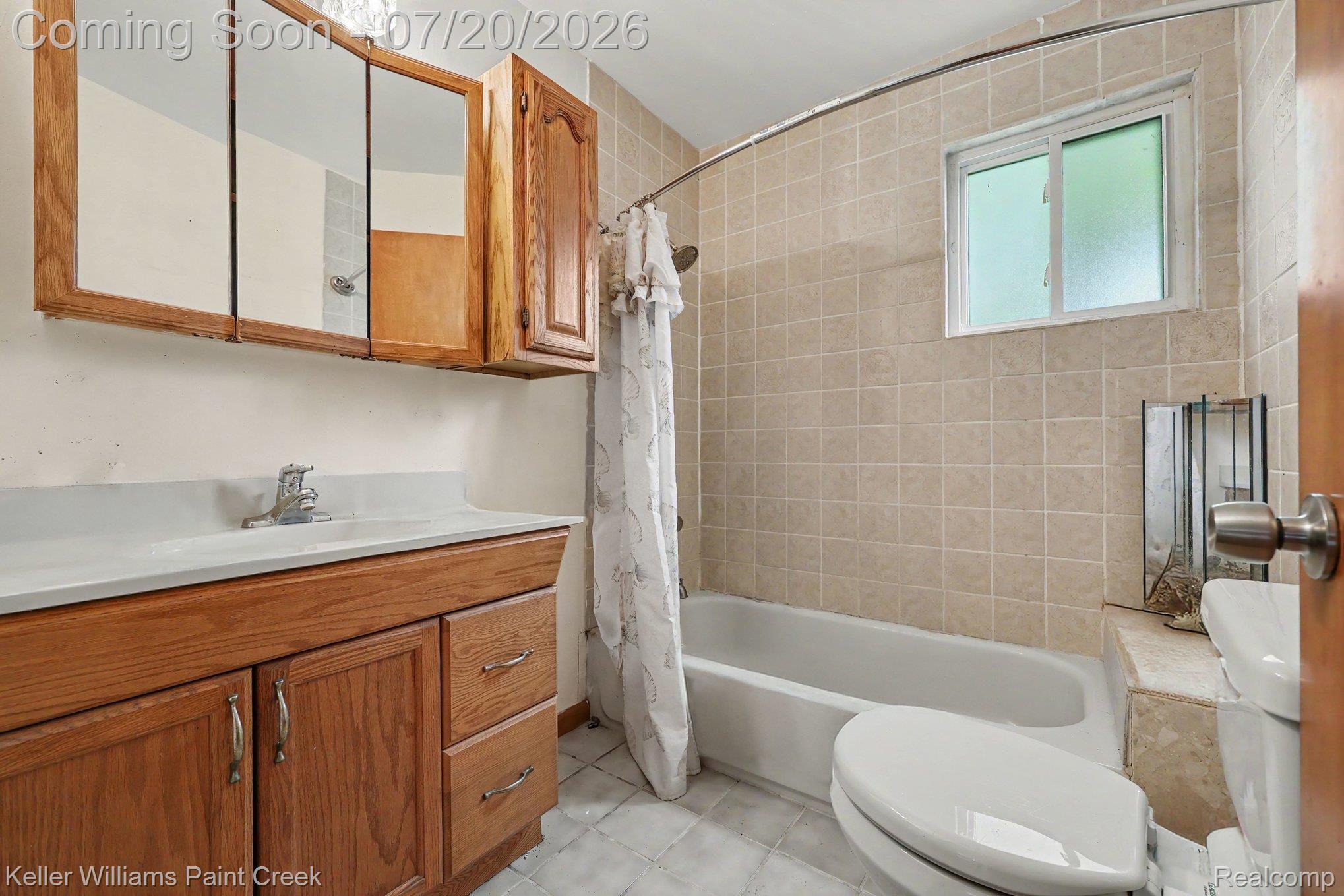 1371 East Leonard Road Leonard, MI 48367 - Photo 14 of 32 Bathroom featuring a wood vanity with integrated sink, tri-fold mirrored medicine cabinet, and a shower/tub combination with tiled surround
