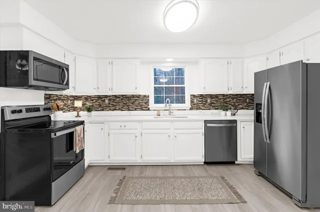 a kitchen with white cabinets stainless steel appliances and sink