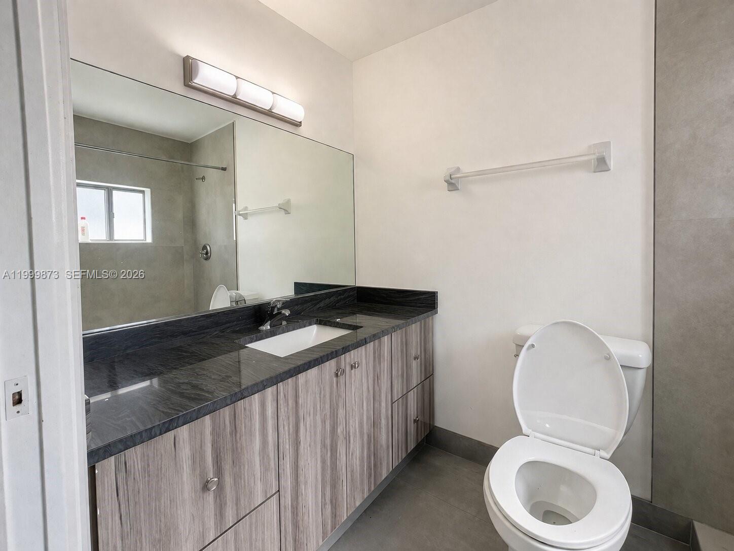 7952 West 29th Way, Unit 202 Hialeah, FL 33018 - Photo 9 of 12 a bathroom with a granite countertop toilet sink and mirror