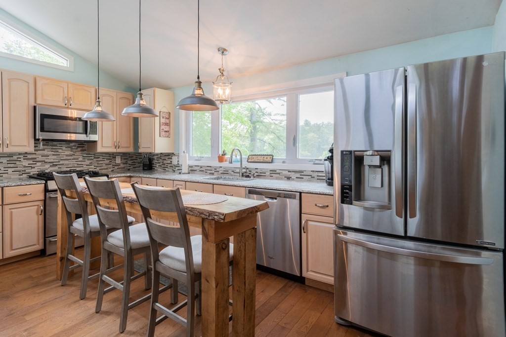 7 Sunset Drive Merrimack, NH 03054 - Photo 9 of 35 a kitchen with stainless steel appliances granite countertop a refrigerator a stove a sink dishwasher a dining table and chairs with wooden floor