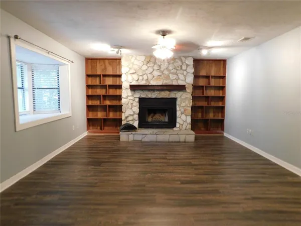 an empty room with windows and fireplace