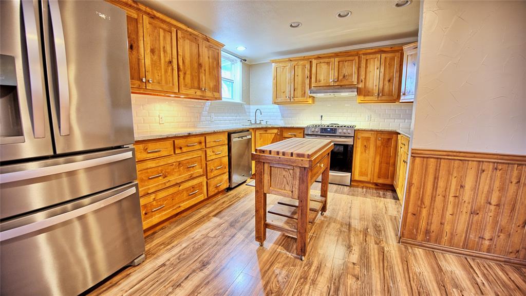 584 West Alamo Road Bowie, TX 76230 - Photo 3 of 40 a kitchen with granite countertop wooden floors and white stainless steel appliances