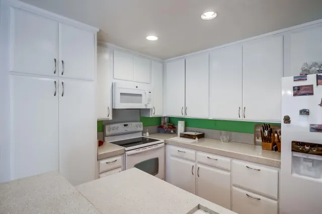 a kitchen with stainless steel appliances white cabinets and a stove top oven
