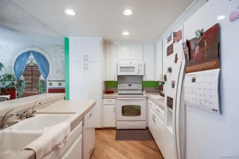 a kitchen with stainless steel appliances granite countertop a refrigerator a stove and a sink with wooden floor