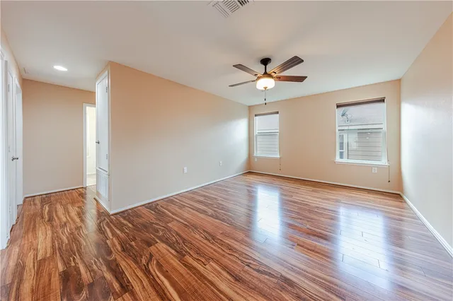 a view of an empty room with window and wooden floor