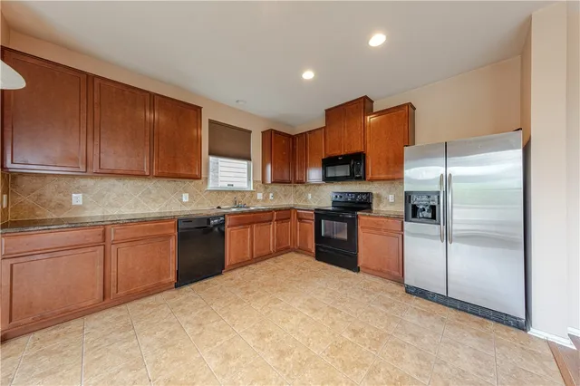 a kitchen with granite countertop stainless steel appliances a refrigerator sink and microwave