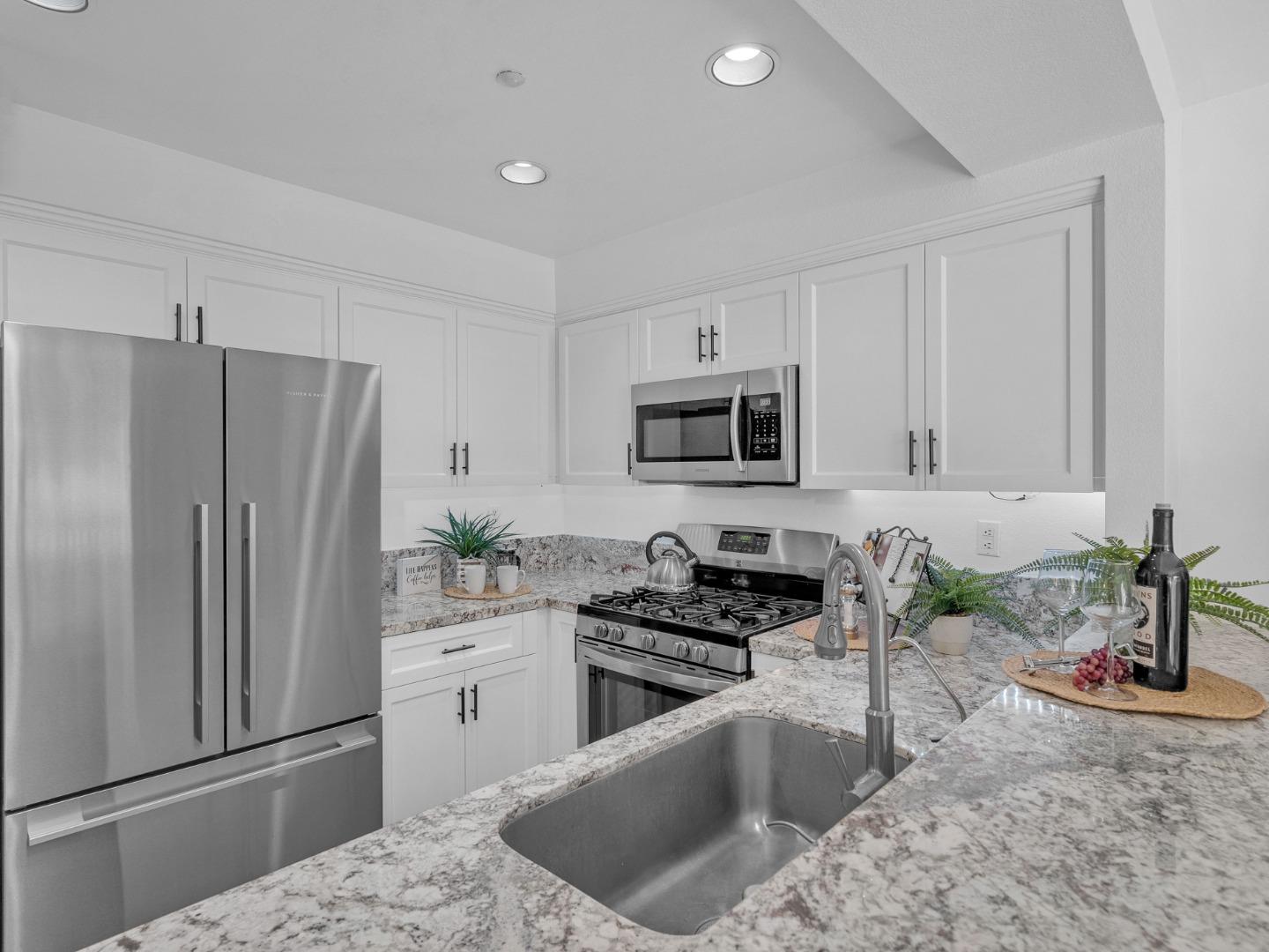 6978 Gregorich Drive, Unit E San Jose, CA 95138 - Photo 12 of 24 a kitchen with stainless steel appliances granite countertop a refrigerator sink and stove