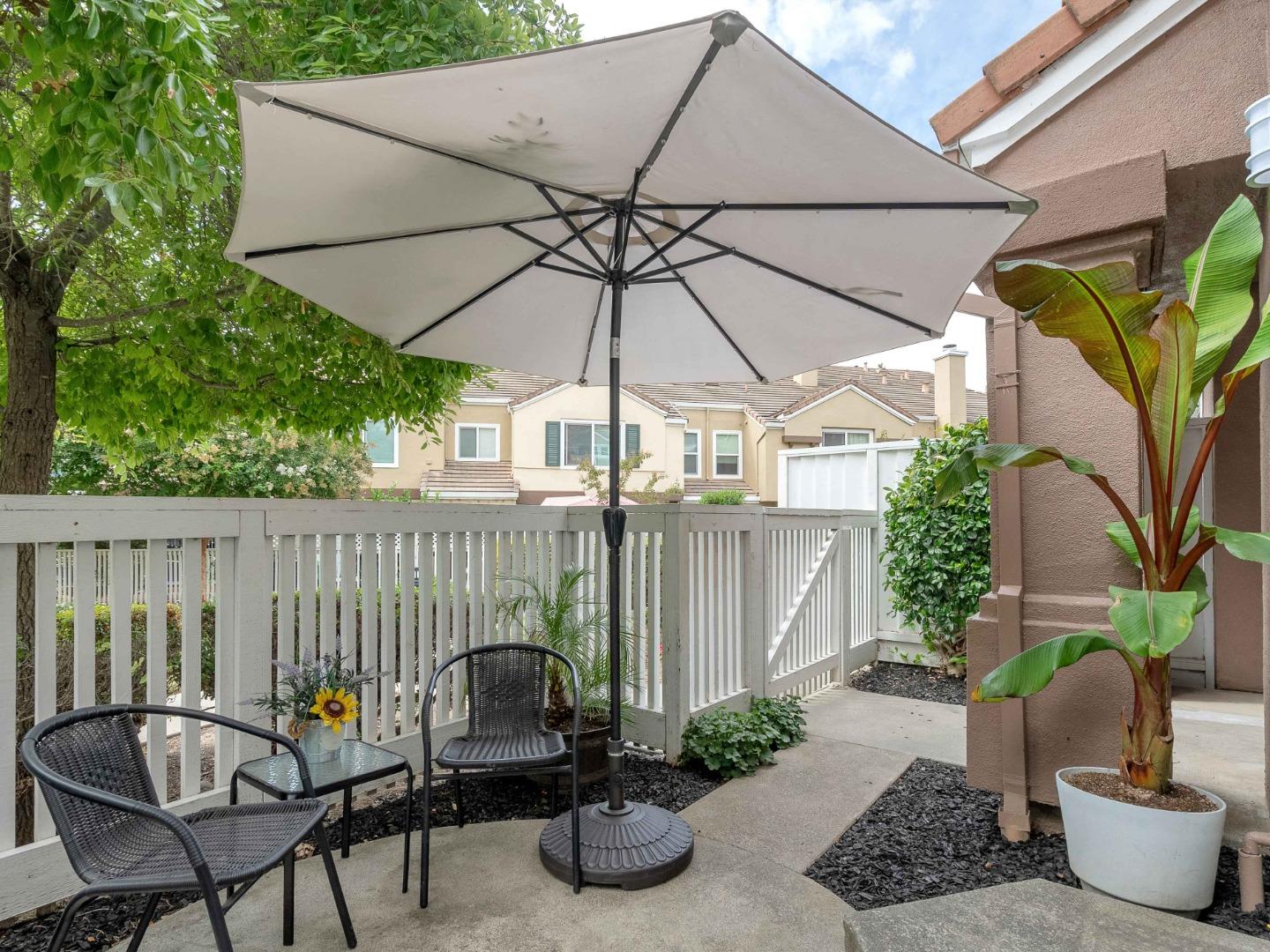 6978 Gregorich Drive, Unit E San Jose, CA 95138 - Photo 23 of 24 a backyard of a house with table and chairs under an umbrella