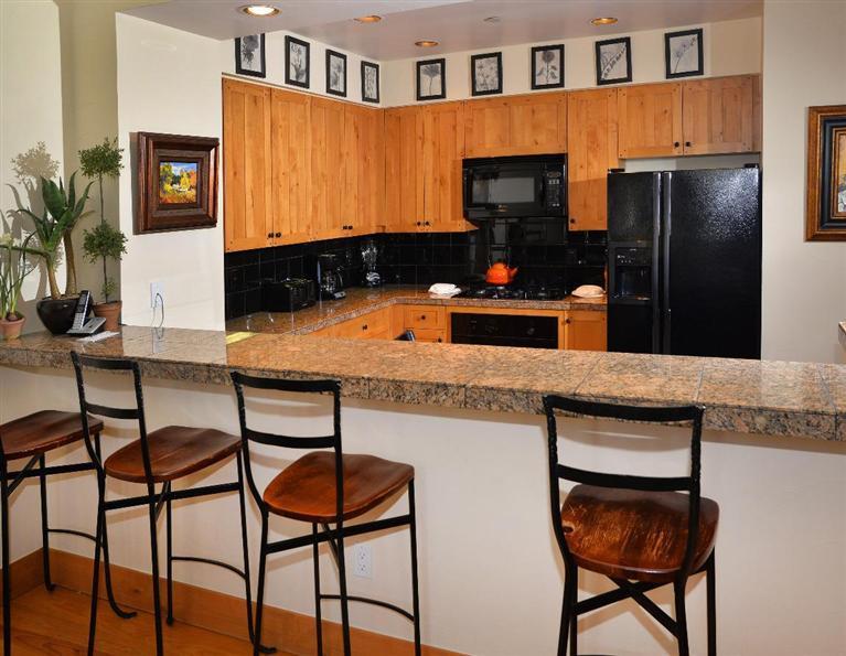 63 Avondale Lane, Unit R215 Beaver Creek, CO 81620 - Photo 7 of 26 a kitchen with stainless steel appliances granite countertop a table chairs in it and wooden floors