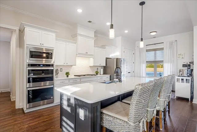 a open kitchen with stainless steel appliances granite countertop a stove and a refrigerator a oven a large island with wooden floor