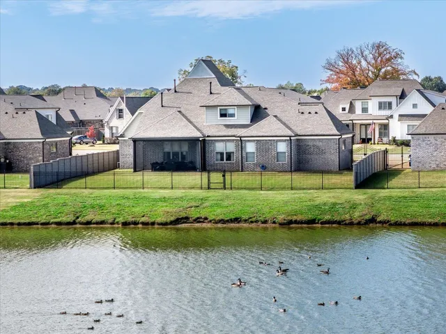 a view of a big house next to a yard and large trees