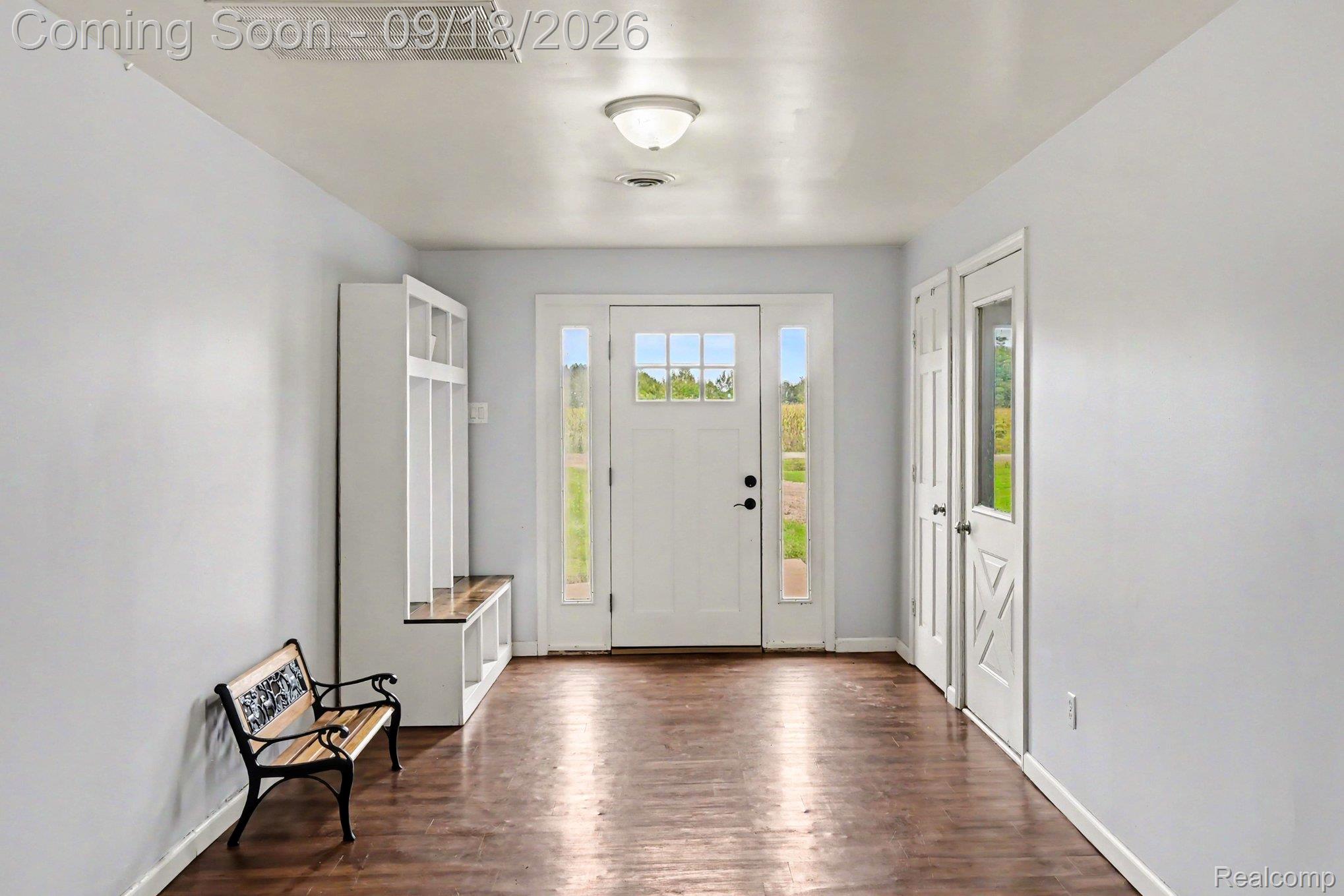 10755 Spencer Road St. Charles, MI 48655 - Photo 8 of 35 Entryway featuring wood-finish flooring, white walls, built-in storage with bench seating, a paneled front door with sidelights, and an overhead light fixture