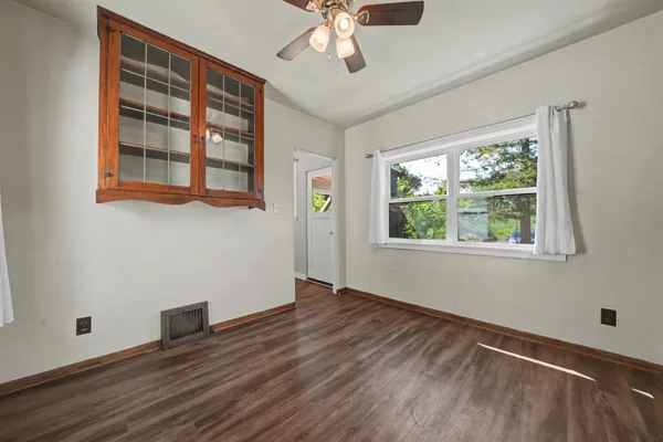 a view of an empty room with wooden floor and a window