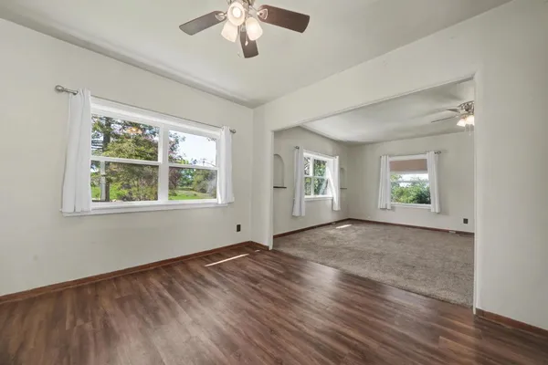a view of an empty room with a window and wooden floor