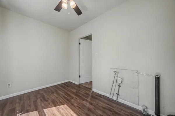an empty room with wooden floor fan and window