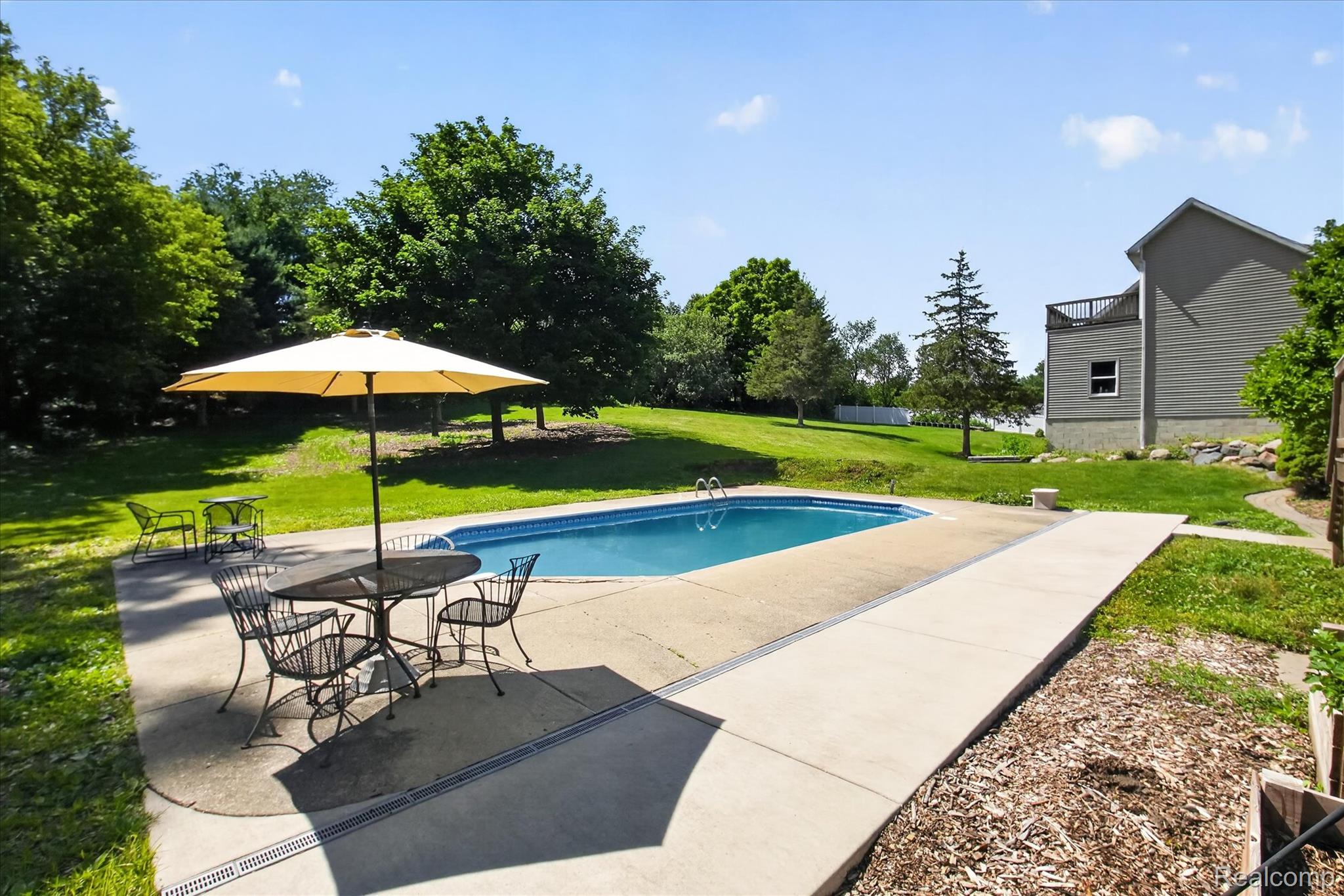 8114 Chilson Road Pinckney, MI 48169 - Photo 24 of 32 In-ground swimming pool featuring a concrete surround and expansive lawn