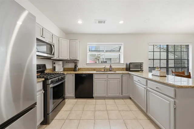 an empty room with chandelier fan and windows