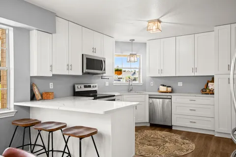 a kitchen with stainless steel appliances a stove a sink a refrigerator and cabinets with wooden floor