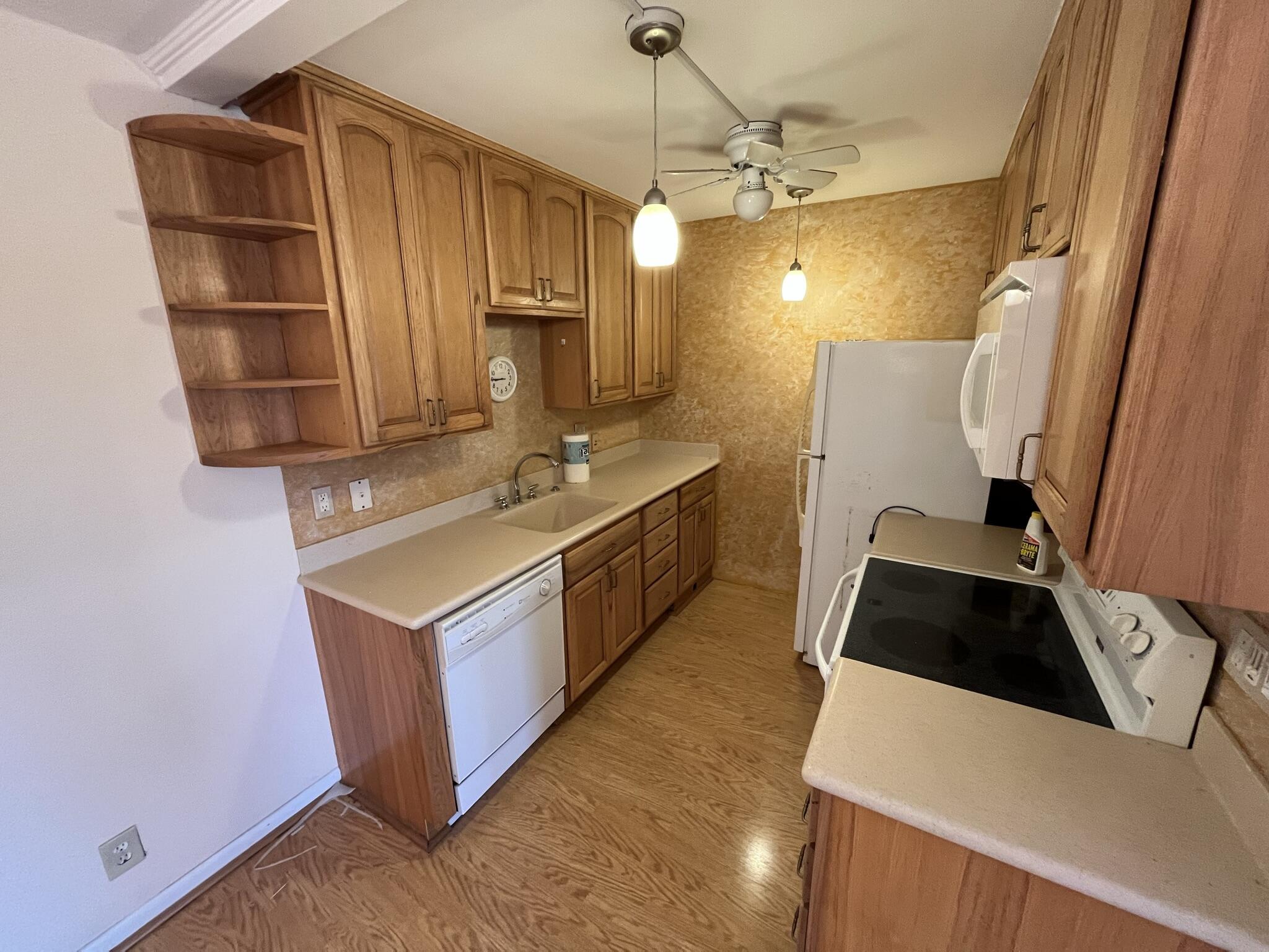 3013 Newcastle A Boca Raton, FL 33434 - Photo 7 of 19 a kitchen with kitchen island a stove a sink and a refrigerator with wooden floor