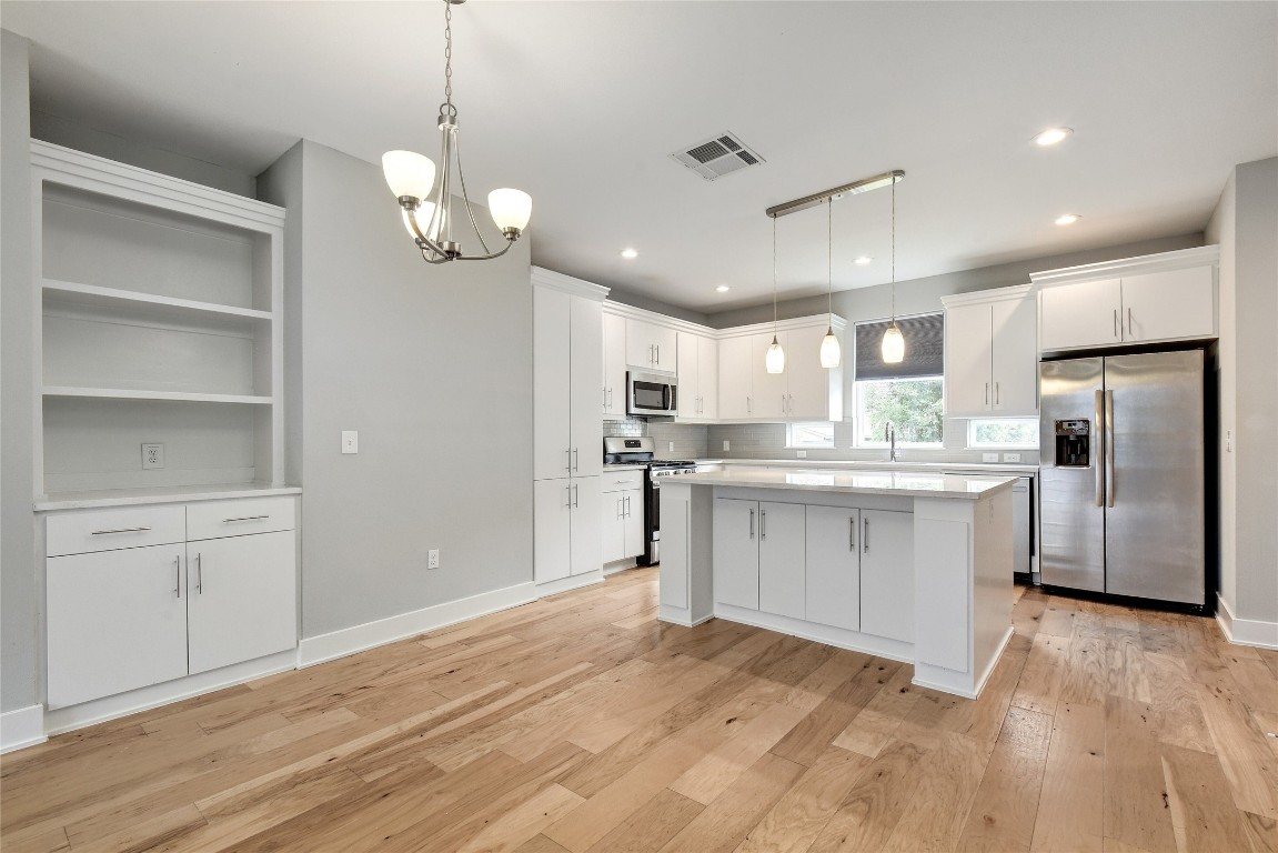 a kitchen with white cabinets stainless steel appliances and window