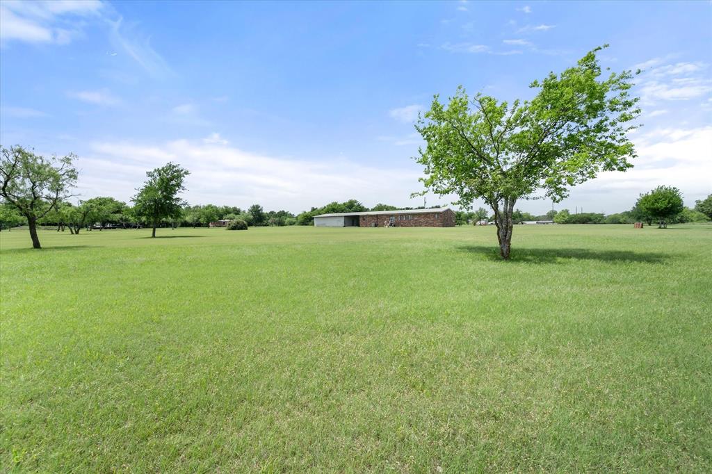 2101 Ridge View Drive Cleburne, TX 76033 - Photo 30 of 31 Expansive green space featuring scattered mature trees and a distant building with a metal roof