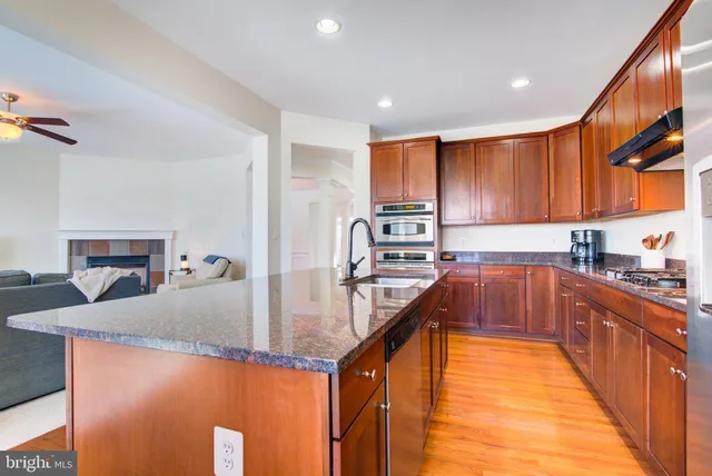 a kitchen with stainless steel appliances granite countertop sink stove refrigerator and cabinets
