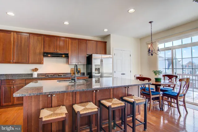 a kitchen with granite countertop a dining table chairs sink and cabinets
