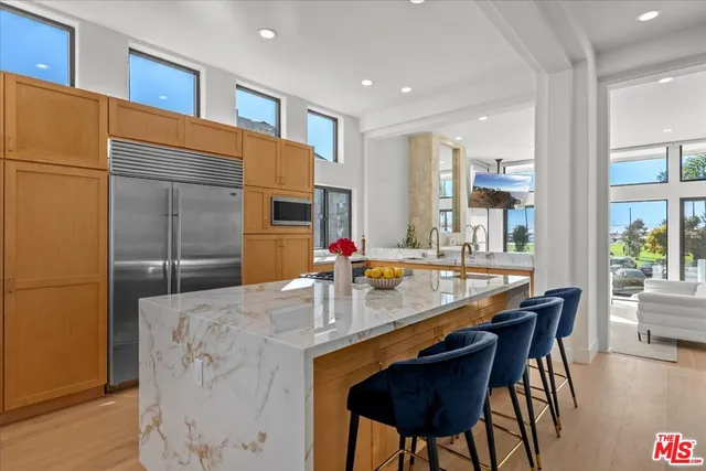 a kitchen with stainless steel appliances kitchen island granite countertop a table chairs in it and wooden floors