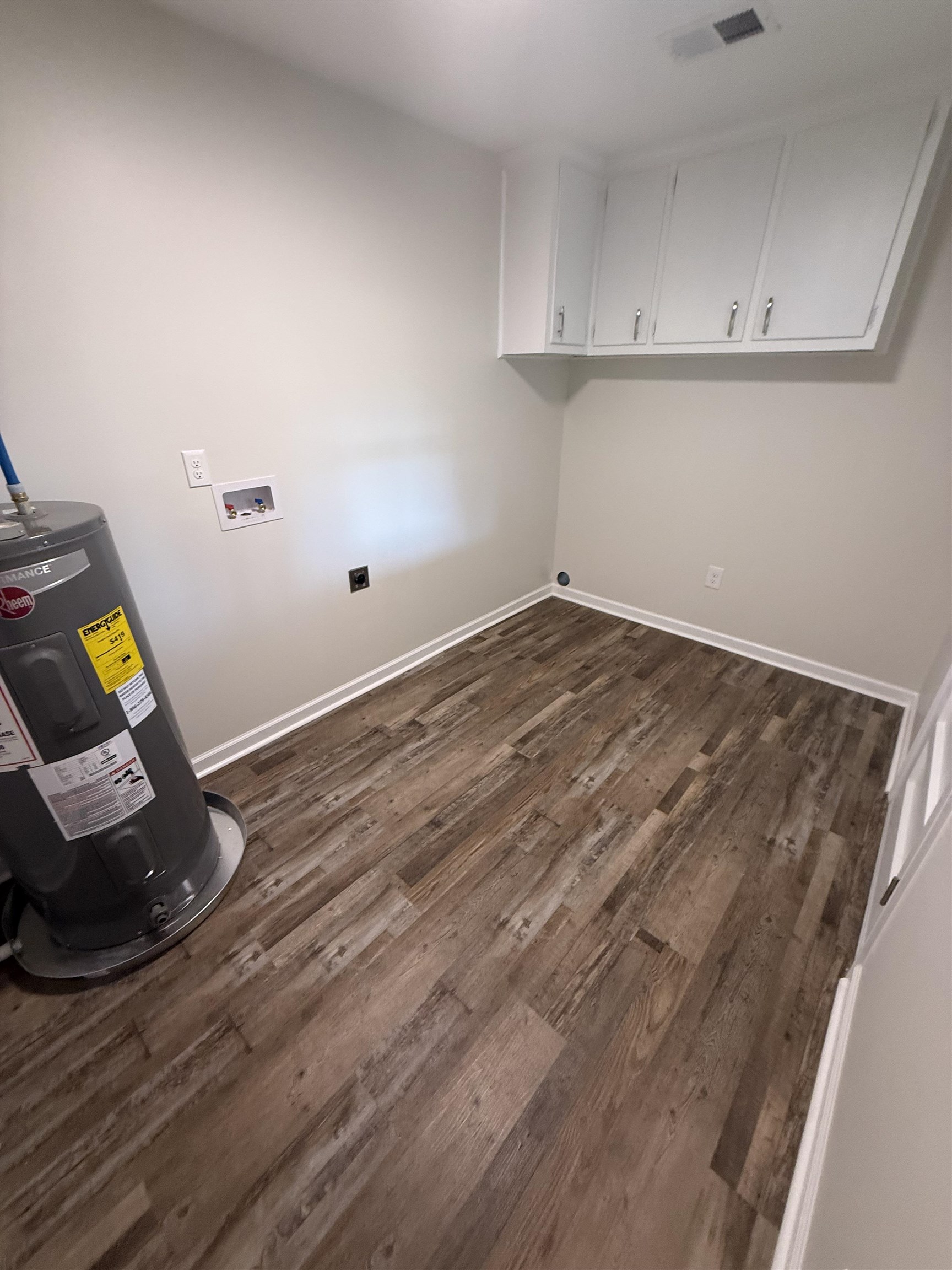 1835 Pleasant Grove Road Moscow, TN 38057 - Photo 33 of 34 Utility area featuring wood-finish flooring, light neutral wall paint, and white upper cabinetry with silver hardware