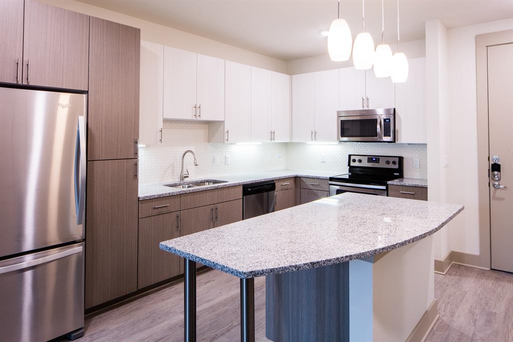 4020 Gilbert Avenue, Unit 201 Dallas, TX 75219 - Photo 4 of 8 a kitchen with stainless steel appliances granite countertop a refrigerator a sink a stove a microwave and wooden floor