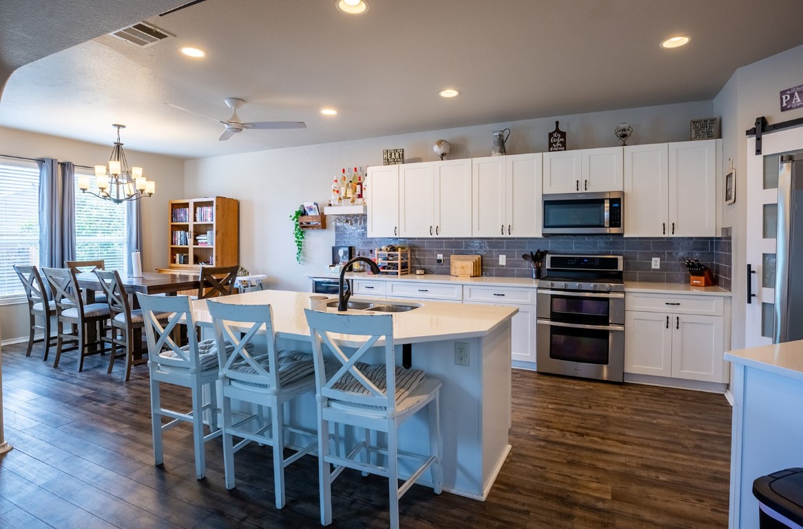 a kitchen with stainless steel appliances a microwave a stove a table and chairs
