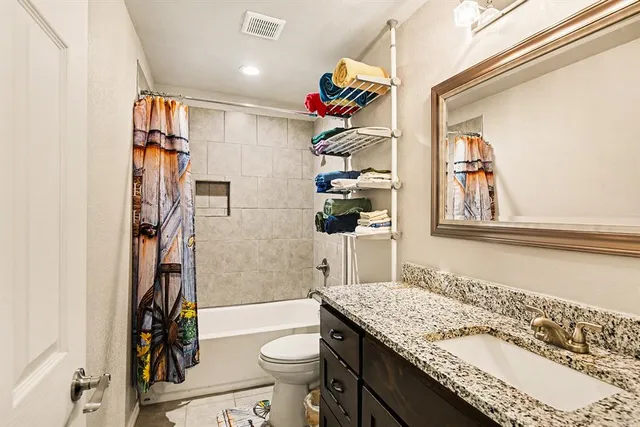 a bathroom with a granite countertop sink a toilet and shower
