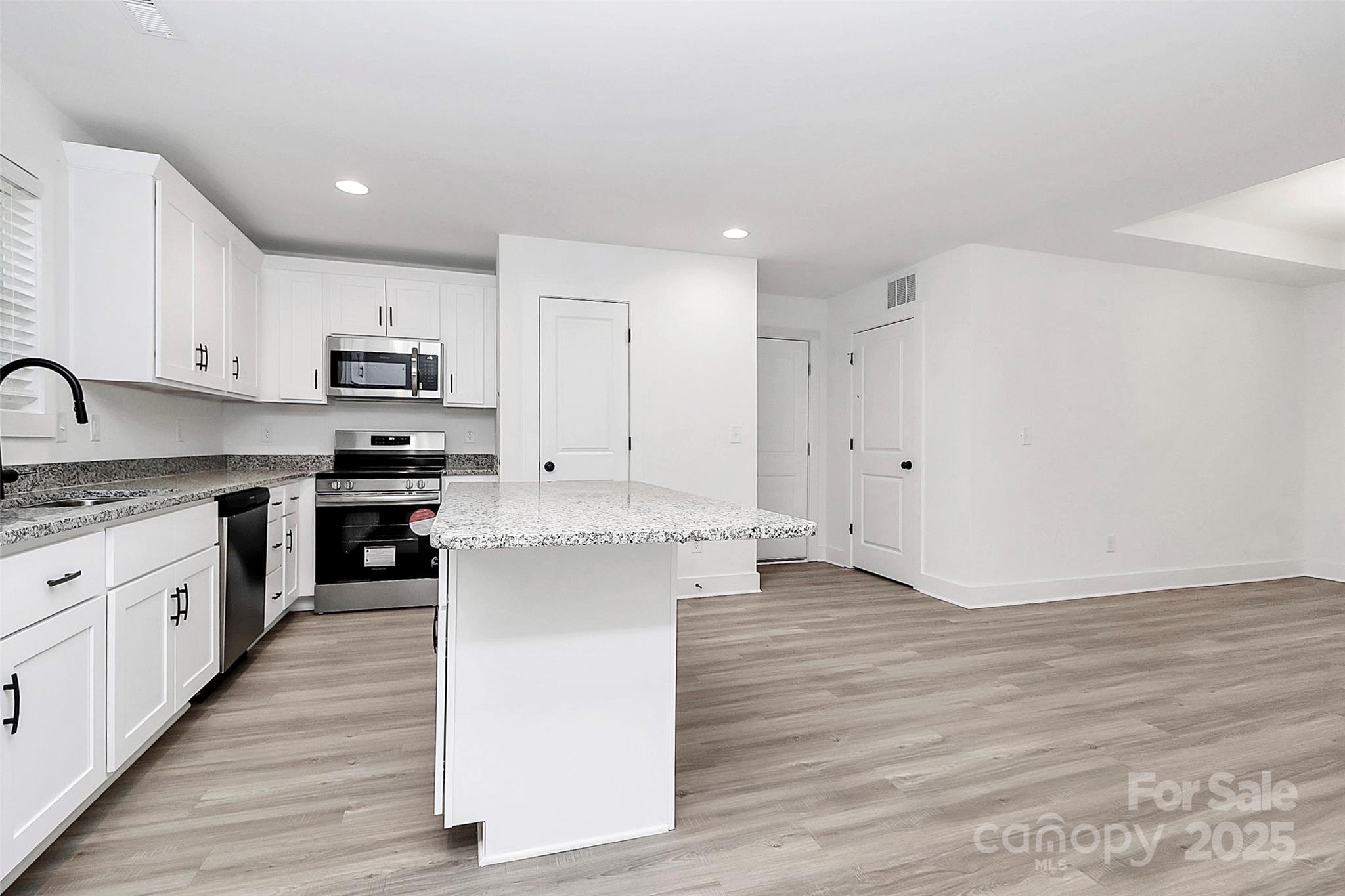 6259 Long Branch Road Salisbury, NC 28147 - Photo 9 of 48 a kitchen with wooden floors and white cabinets