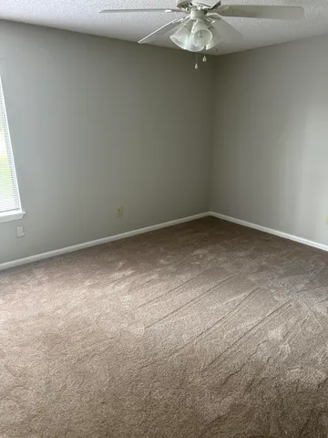 an empty room with a chandelier fan and windows