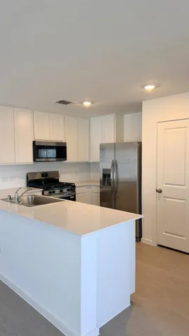 a kitchen with stainless steel appliances a refrigerator a sink a stove and cabinets