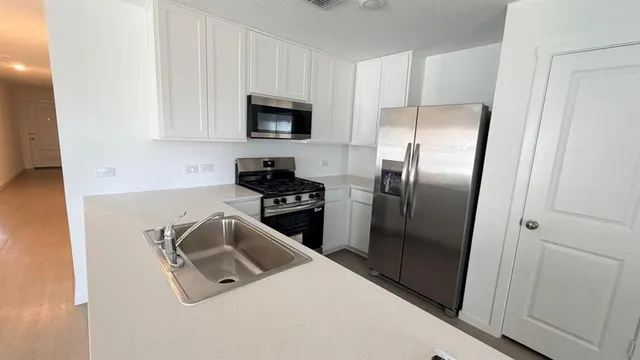 a kitchen with stainless steel appliances a stove a sink and a refrigerator