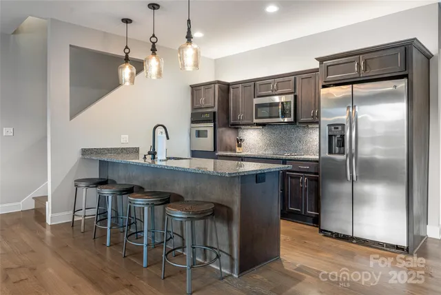 a kitchen with kitchen island a counter top space a sink stainless steel appliances and cabinets