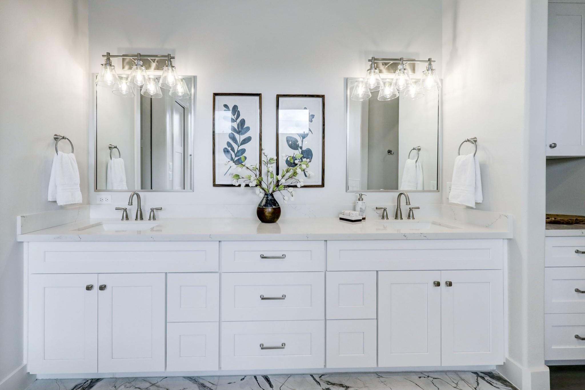 3827 Arlington Street Houston, TX 77018 - Photo 25 of 39 Closer view of double vanity with sleek white cabinetry and marble countertops. It includes two mirrors with modern light fixtures and elegant decor, creating a bright and sophisticated space.