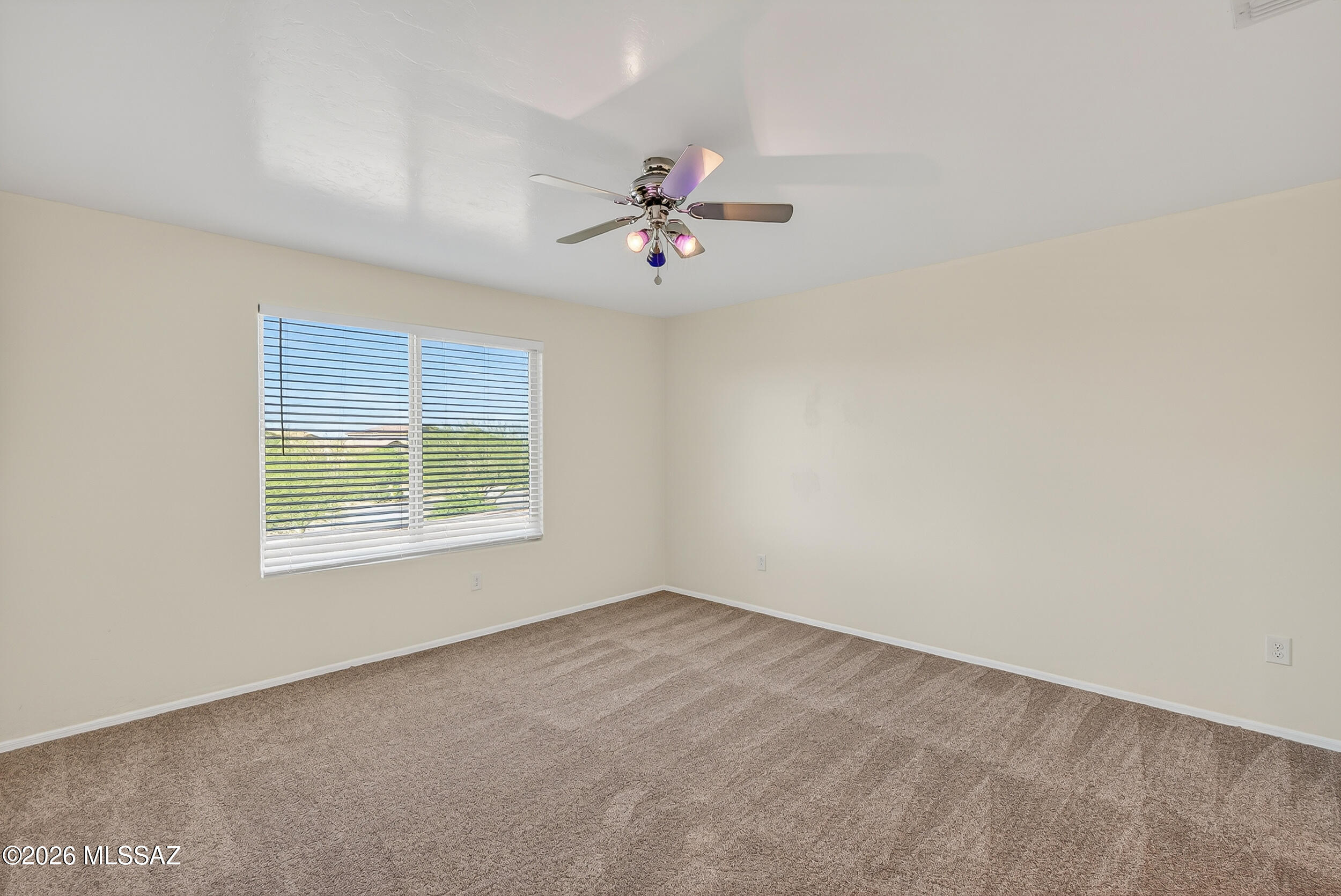 7556 South Circulo Rio Blanco Tucson, AZ 85756 - Photo 20 of 50 Expansive primary owner’s suite with fresh plush carpeting throughout. Highlights include a large ceiling fan with lights, neutral palette, and convenient access to the private bathroom and generous walk-in closet — your personal sanctuary.