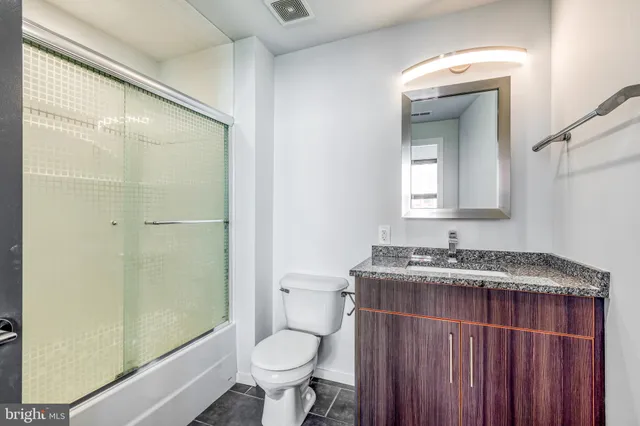 a bathroom with a granite countertop sink toilet and shower