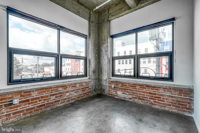 a view of an empty room with wooden floor and windows