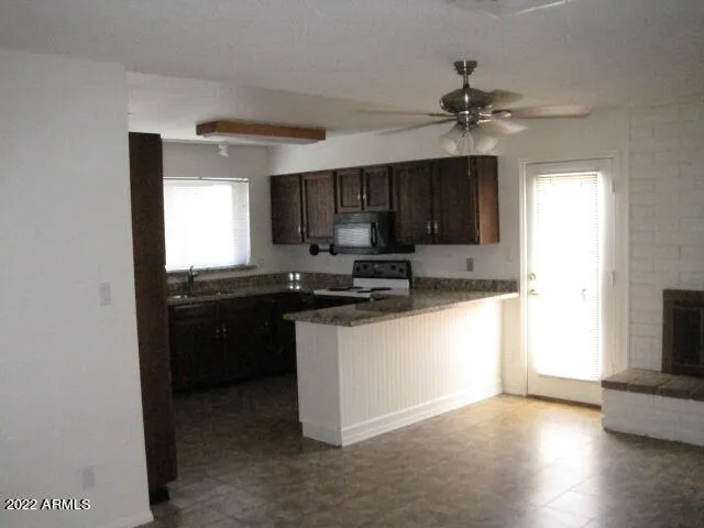 a kitchen with granite countertop a refrigerator a sink and wooden cabinets