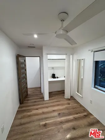 a view of a hallway to a livingroom with wooden floor and a ceiling fan