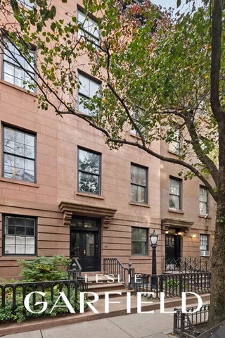 a view of a brick house with large windows and a large tree